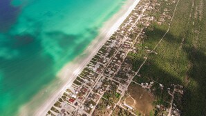 Vue aérienne d’une zone côtière avec une plage et un quartier résidentiel.