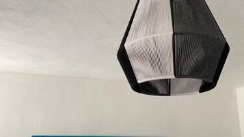 Una habitación con una lámpara colgante de diseño geométrico en negro y una obra de arte mural con degradado azul.