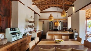 Una cocina amplia con armarios de madera, un comedor con una mesa preparada para cuatro comensales y vistas al exterior.