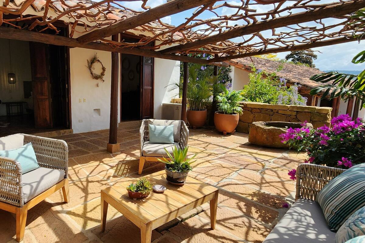 A patio area with wicker furniture, a wooden table, and potted plants.