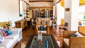 Un espacio habitable amplio con techo alto, muebles de mimbre y una mesa de centro.