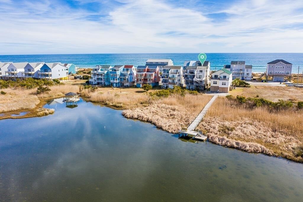 A coastal residential area with houses along the water, a dock, and a clear view of the ocean.