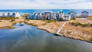 A coastal residential area with houses along the water, a dock, and a clear view of the ocean. - BEACH PLEASE! Amazing Ocean and Sound Views with Easy Beach Access! Pet Friendly (North Topsail Beach)