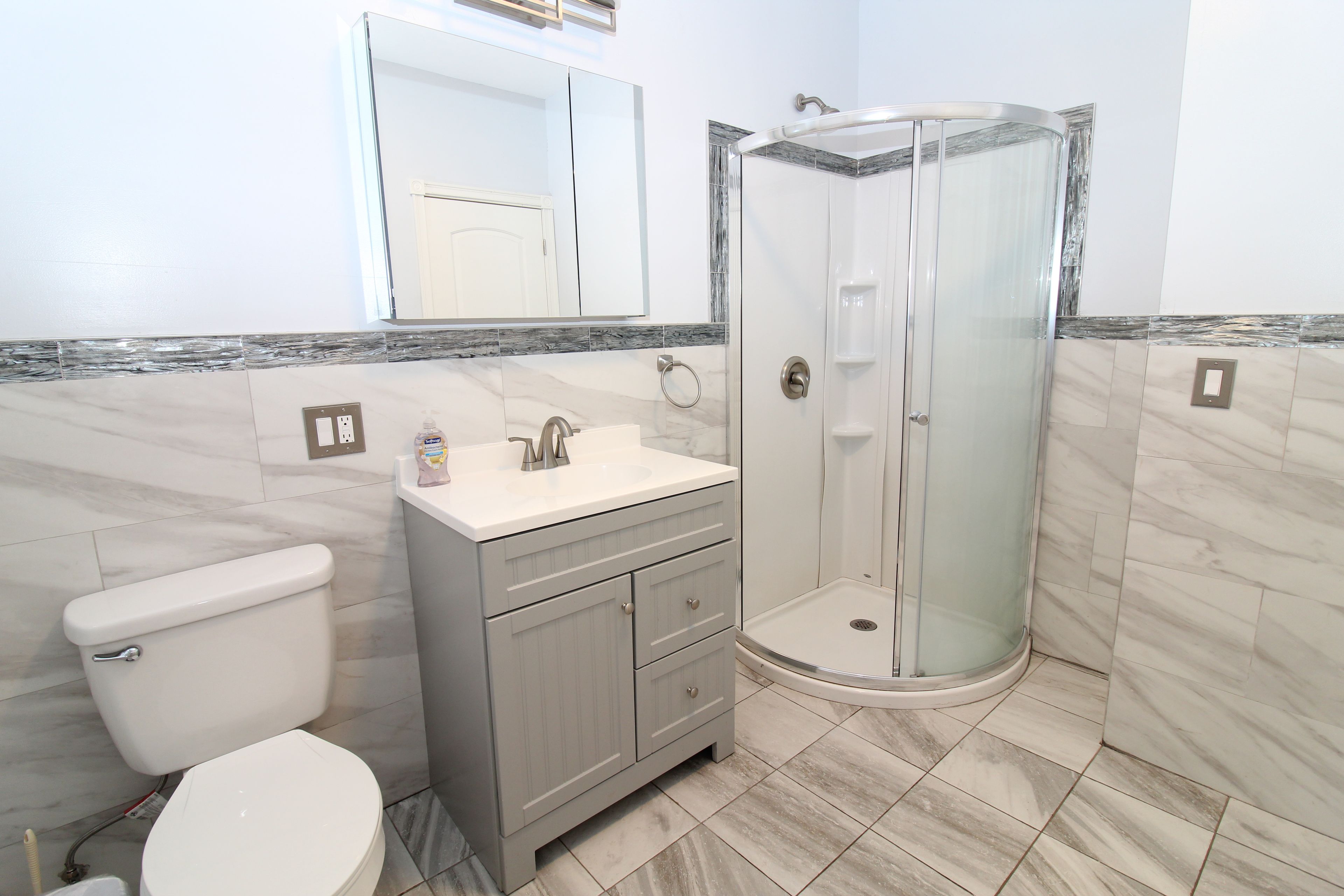 A bathroom with a toilet, vanity, and a glass-enclosed shower stall.