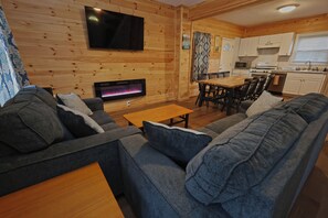 A cozy living room with a sofa, a coffee table, and a fireplace. - Catskill House near downtown /w Hot tub, Sauna, Game room, Pool, Near Ski resort (Tannersville)