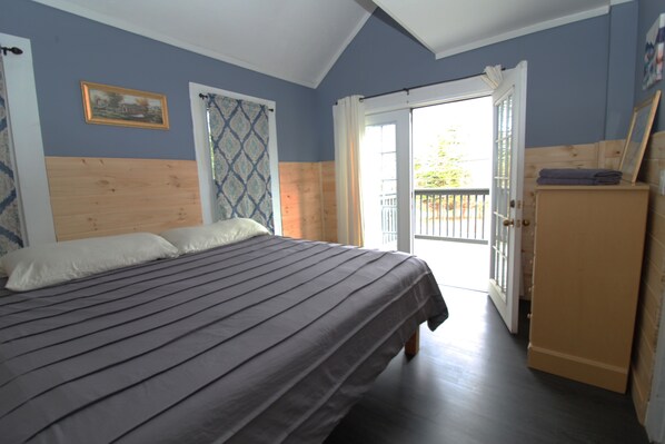 Un dormitorio con una cama, cabecera de madera, una puerta que da a un balcón y un armario.