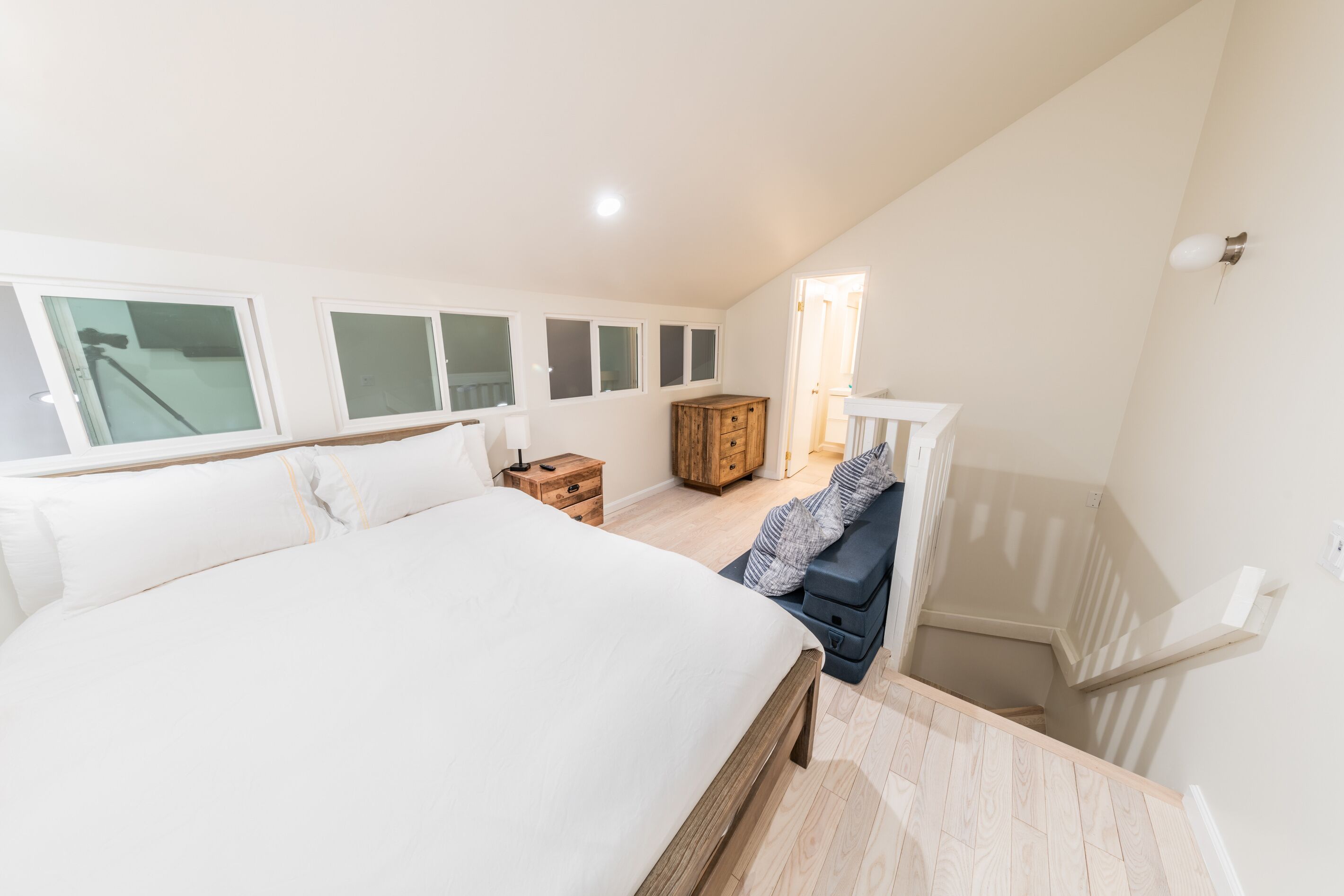 A bedroom with a large bed, a wooden dresser, and a bench with pillows.