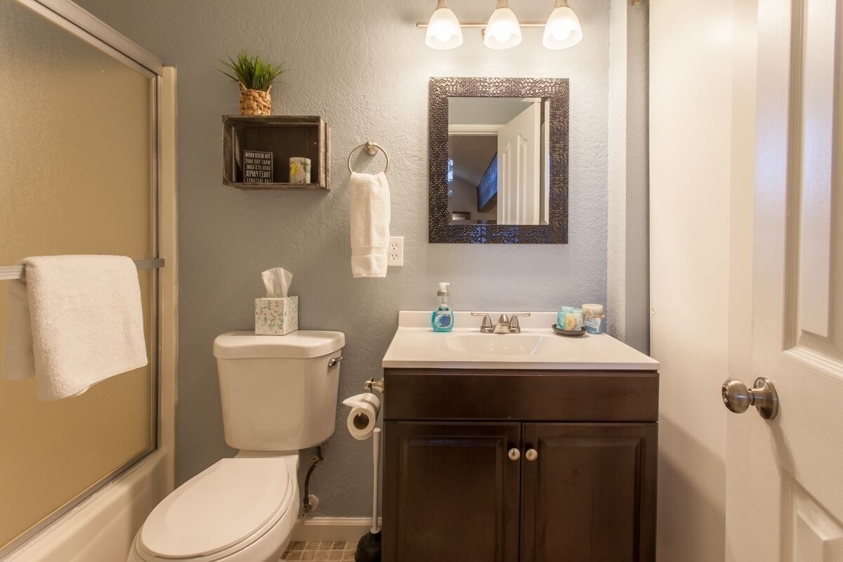A bathroom with a toilet, sink, mirror, and towel rack.