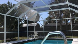 Ein klares, blaues Schwimmbecken mit einer Metallleiter, umgeben von einer weißen Pergola.