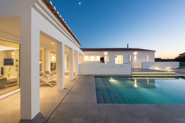 A modern house with a swimming pool, large windows, and a well-lit exterior. - Vila Dria: modern luxury in the best part of the Algarve (Silves)