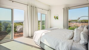 A bedroom with a large bed, sliding glass doors leading to a balcony with a view of the countryside. - Vila Dria: modern luxury in the best part of the Algarve (Silves)