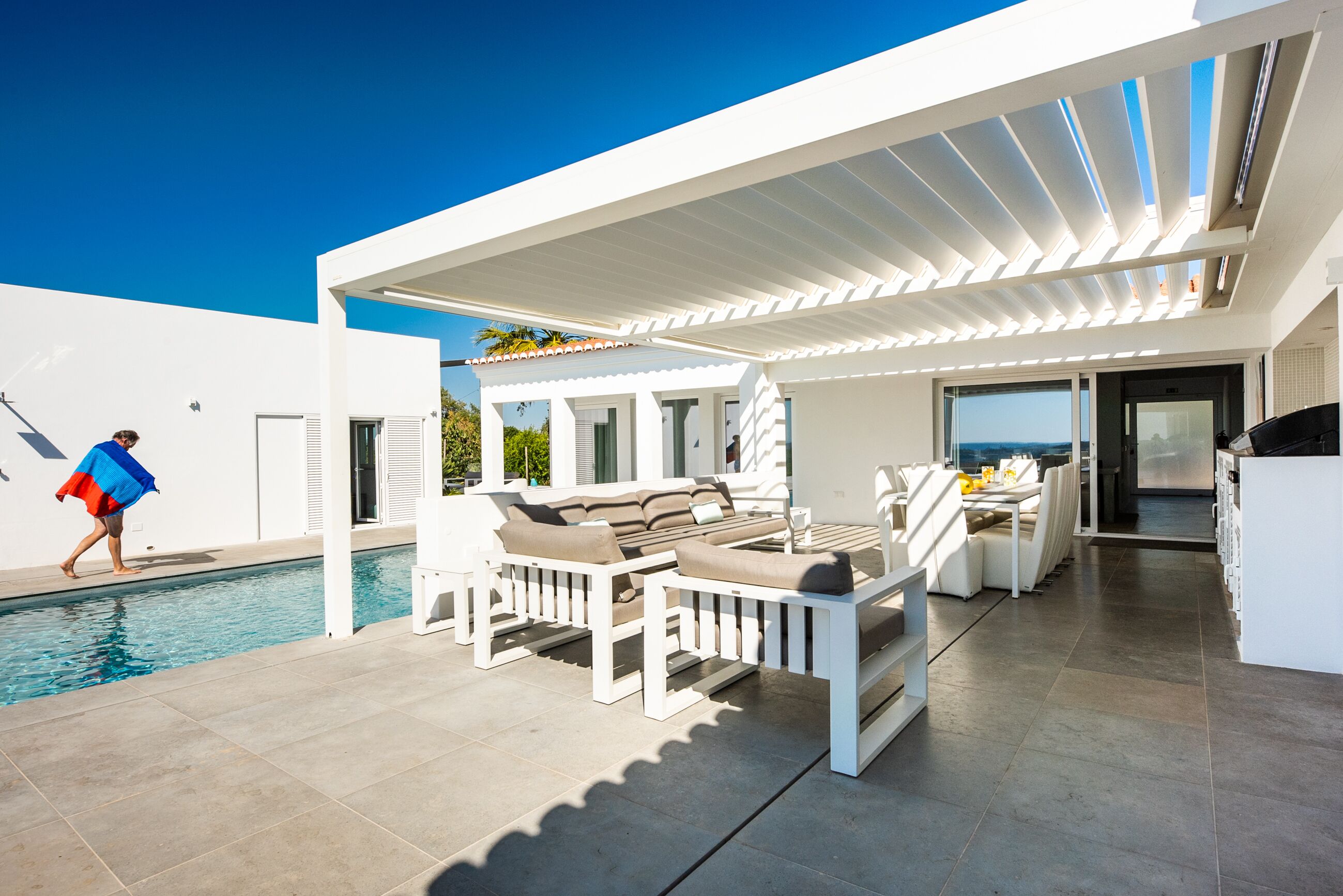 Ein moderner Außenbereich mit Pool, weißen Möbeln und Blick auf den Ozean.