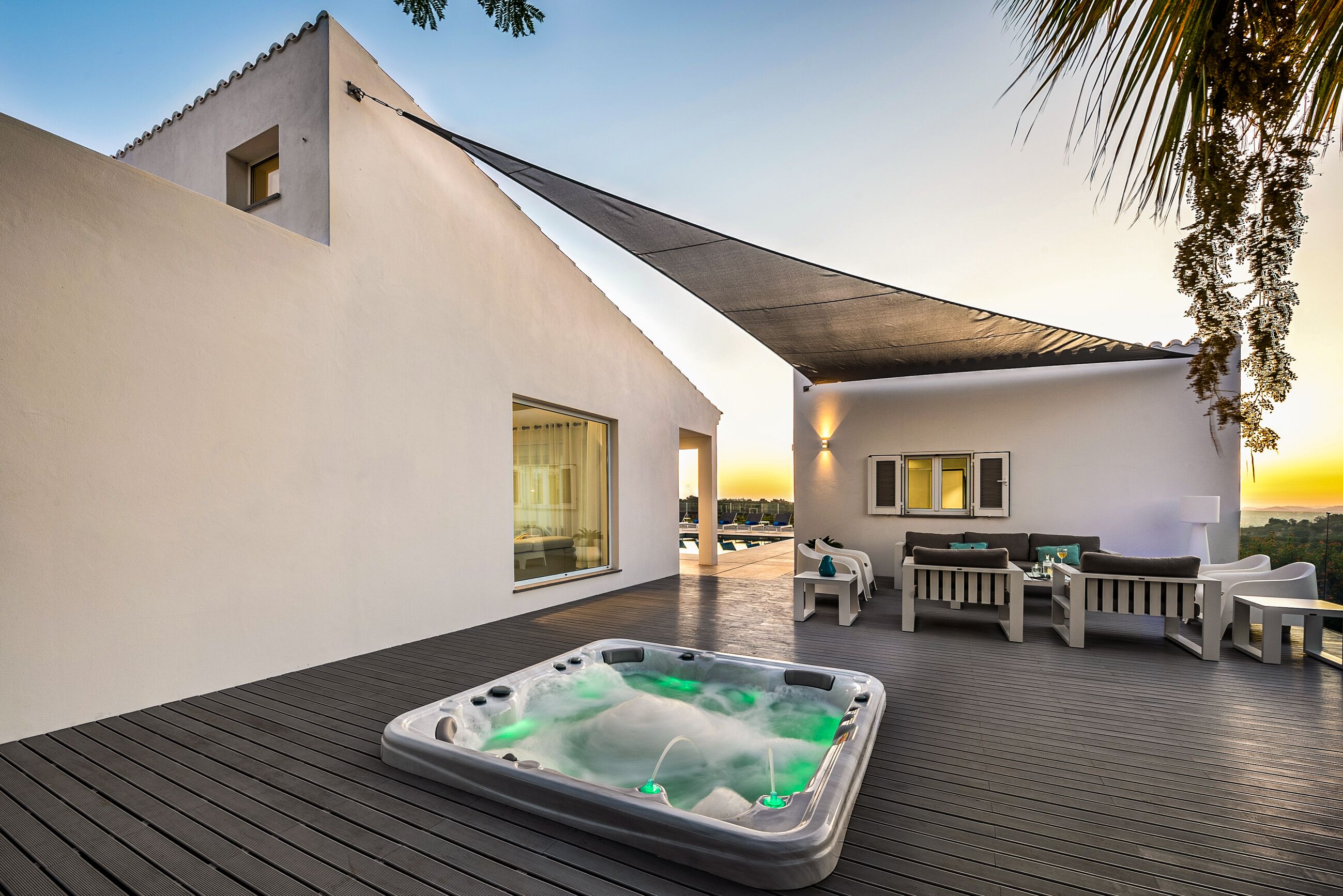 Une terrasse sur le toit avec un jacuzzi, des sièges d’extérieur et une vue sur le coucher de soleil.