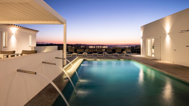 A rooftop pool with lounge chairs and a view of the city skyline at dusk. - Vila Dria: modern luxury in the best part of the Algarve (Silves)