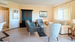 A living room with a sofa, two armchairs, a coffee table, a lamp, and a painting on the wall.