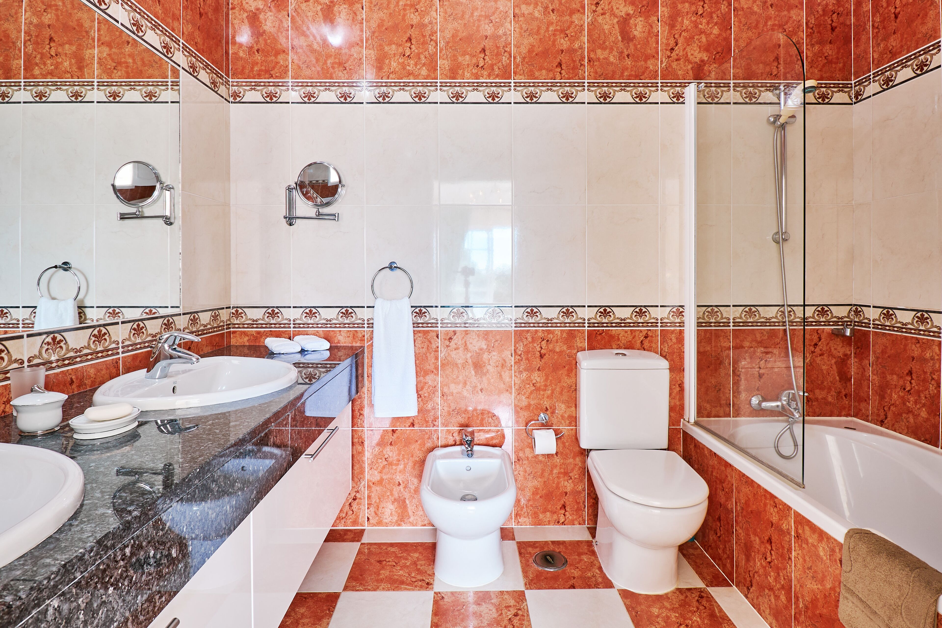 A bathroom with two sinks, a bidet, a toilet, and a bathtub.
