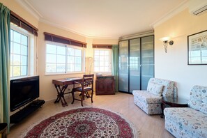 A living room with a TV, a dining table, and a sofa.