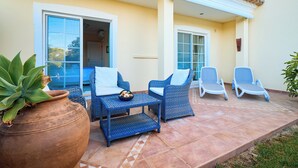 An outdoor seating area with wicker furniture and a large potted plant.