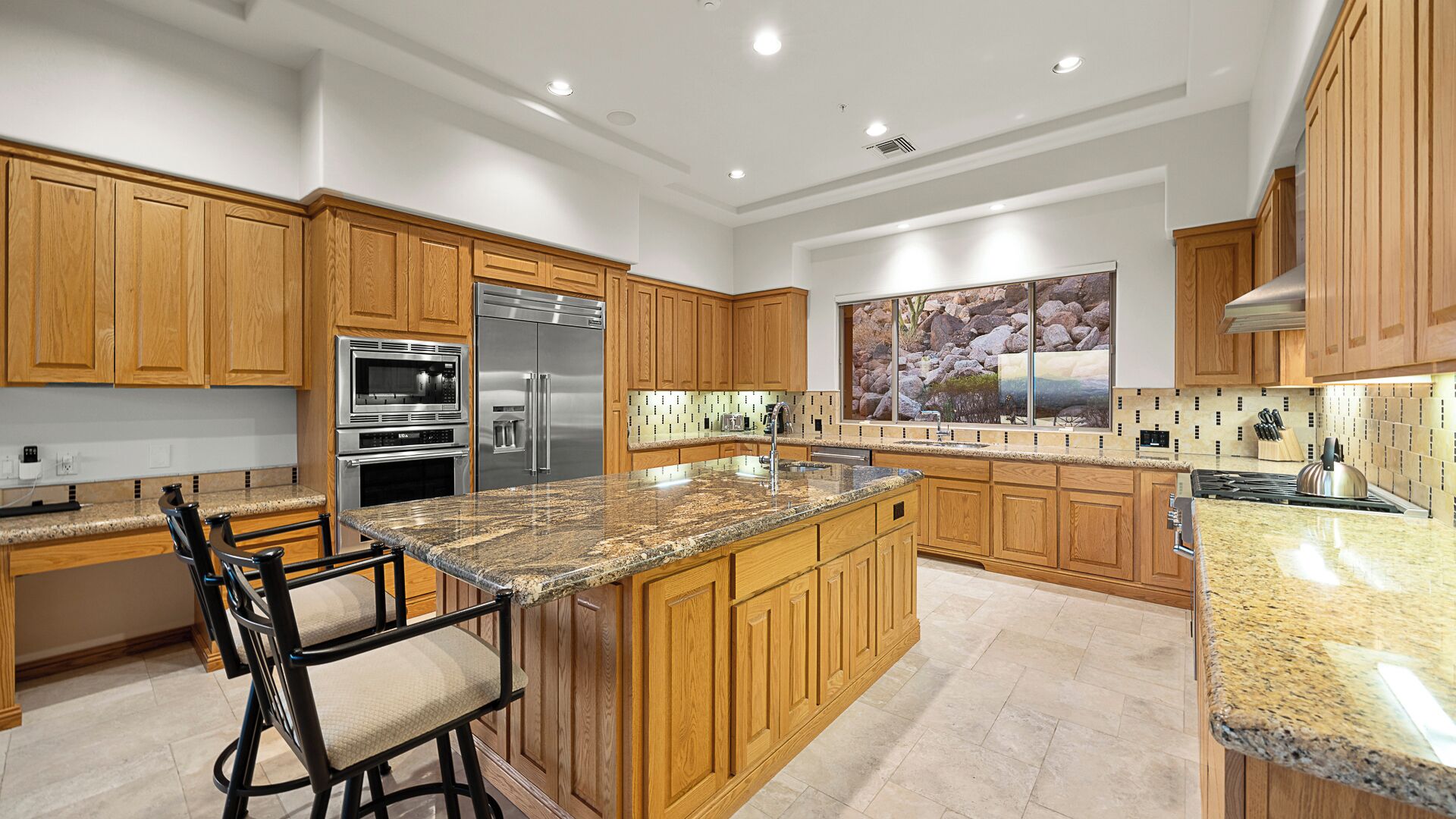 A modern kitchen with wooden cabinets, stainless steel appliances, granite countertops, and a large island with bar stools.