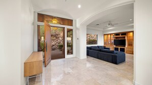 A spacious living area with a large sofa, a wooden cabinet, and a television. - Camelback Heights - 8BR Estate w/ Pool, Theater & Camelback Views (Phoenix)