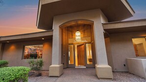 A modern building with a prominent entrance featuring a large arched doorway and a hanging light fixture. - Camelback Heights - 8BR Estate w/ Pool, Theater & Camelback Views (Phoenix)