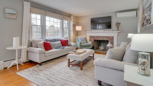 A living room with a fireplace, a sofa, a coffee table, and a television. - Rail Trail Access: Home 2 Mi to Lighthouse Beach! (Chatham)