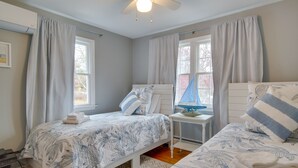 A bedroom with two beds, a small table with a globe, and a window with curtains. - Rail Trail Access: Home 2 Mi to Lighthouse Beach! (Chatham)
