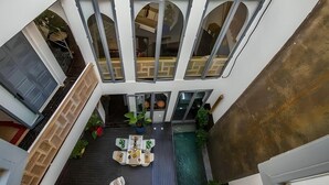 Un edificio moderno con piscina en la azotea, zona de estar al aire libre y amplios ventanales.