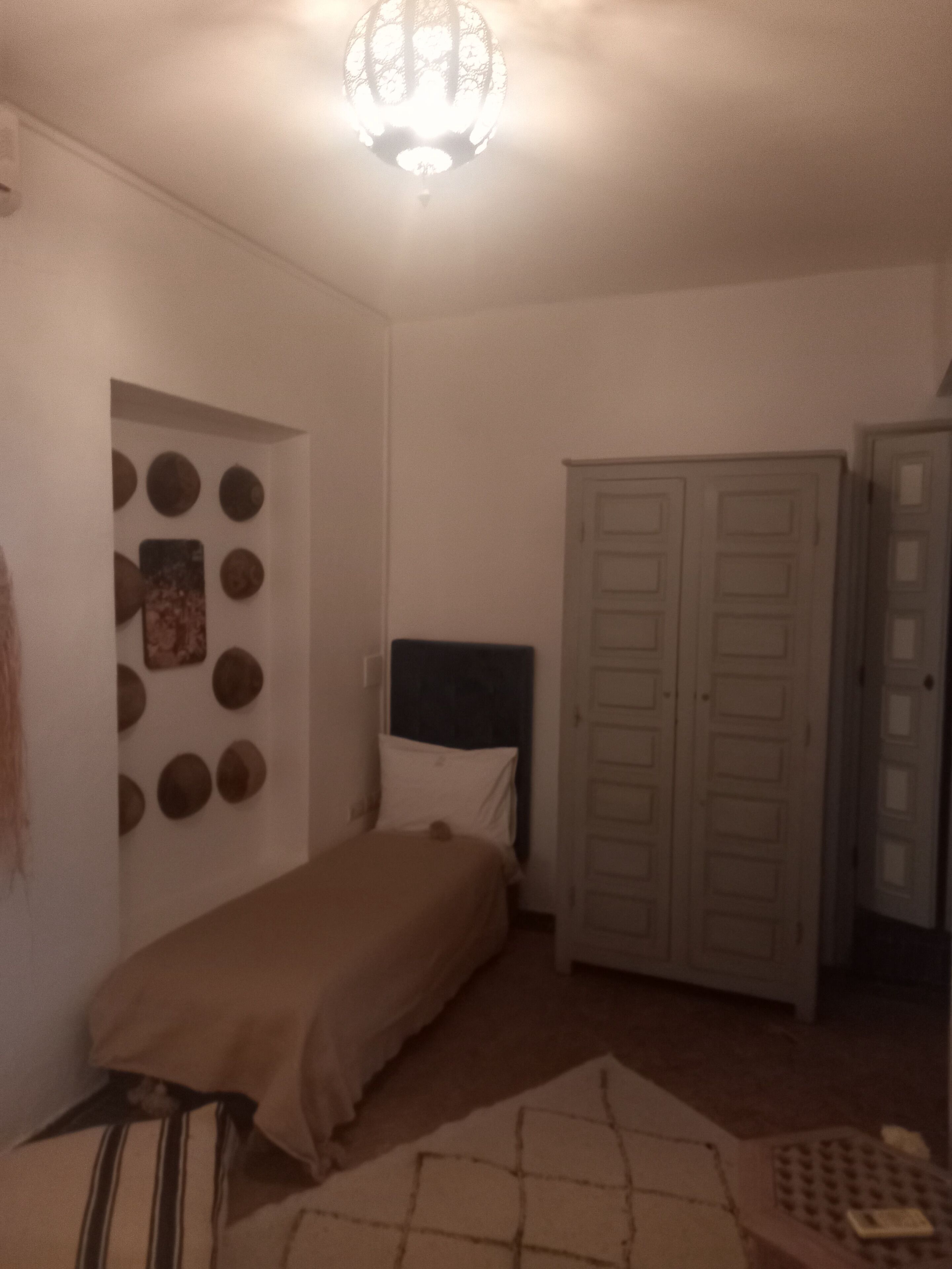 Une chambre à coucher comprenant un lit, une armoire et un mur décoré de motifs circulaires.