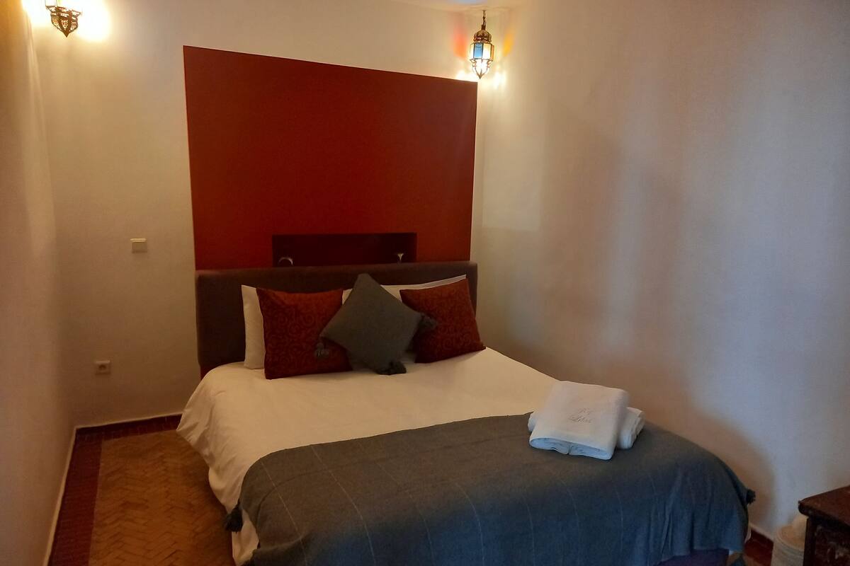 Une chambre d’hôtel avec un grand lit, une tête de lit et une table de chevet.