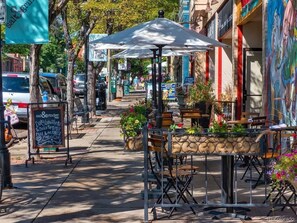 A street with outdoor seating, a chalkboard menu, and a 'no parking' sign. - Bright & Stylish Home Away From Home w Spacious Bedrooms + Game Room (Wheat Ridge)