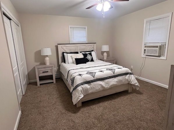 A bedroom with a bed, two bedside tables, a ceiling fan, and an air conditioning unit. - Peaceful home in mount bethel, PA (Mount Beth)