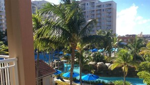 Ein Resort mit Poolbereich, Palmen und Blick auf ein mehrstöckiges Gebäude im Hintergrund.