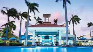 Ein Resort mit Swimmingpool, Palmen und einem Gebäude mit rotem Ziegeldach.