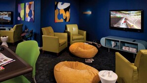 Ein moderner Lounge-Bereich mit bequemen Sitzgelegenheiten, einem Fernseher und abstrakter Wandkunst.