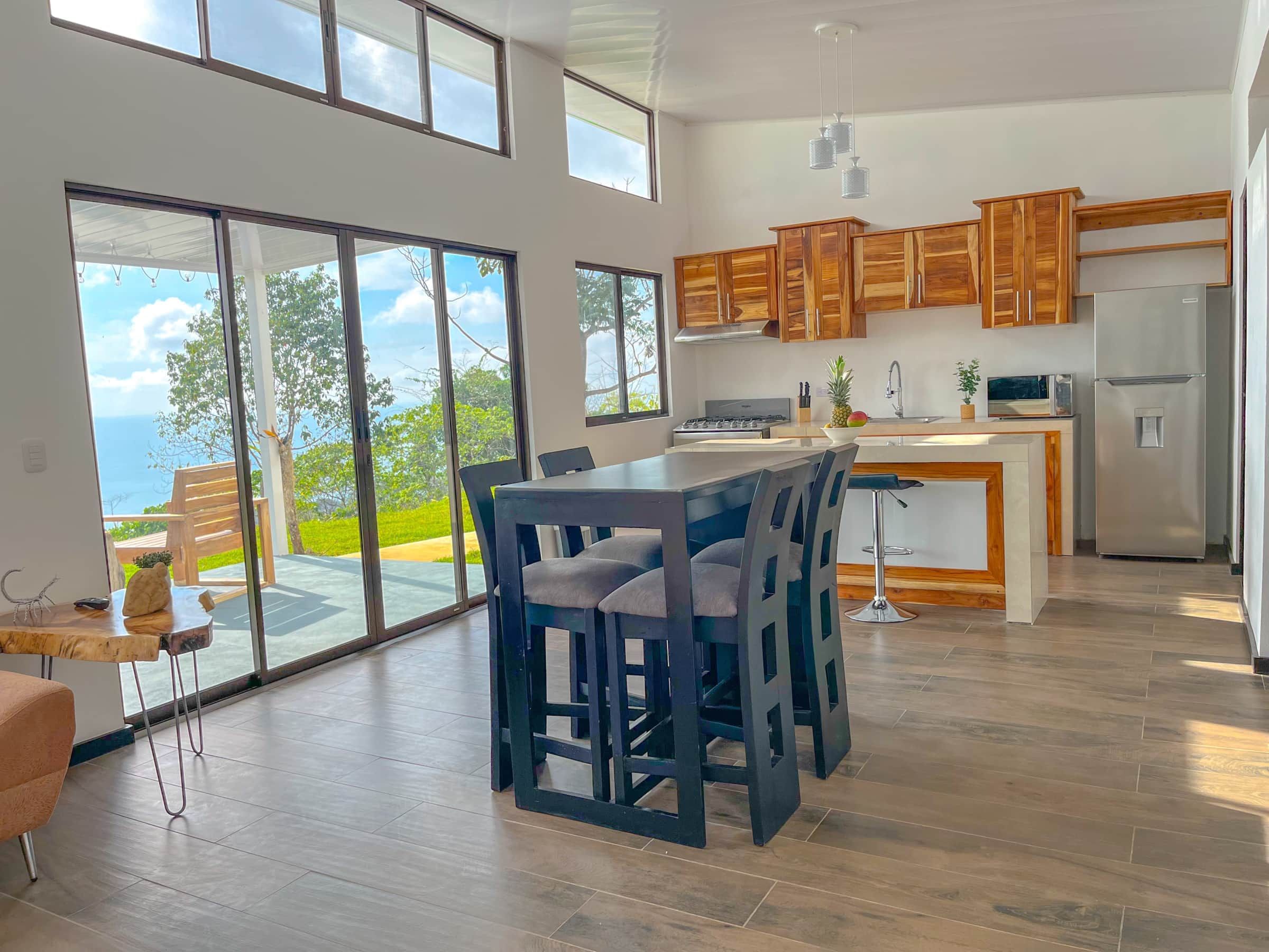 A modern kitchen with wooden cabinets, a stainless steel refrigerator, and a large island with bar stools.