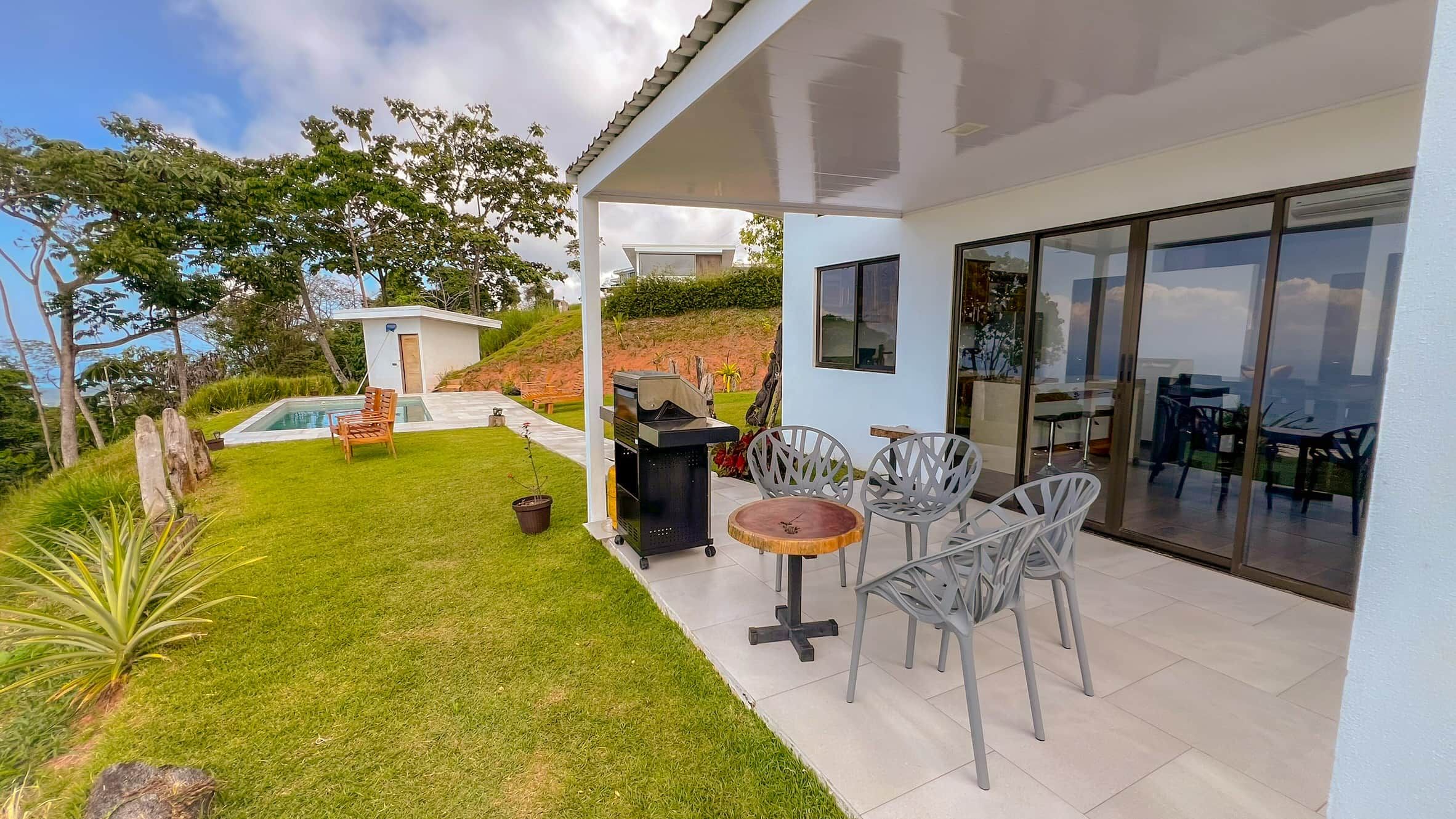 A modern house with a covered patio, a swimming pool, and a dining area with outdoor furniture.