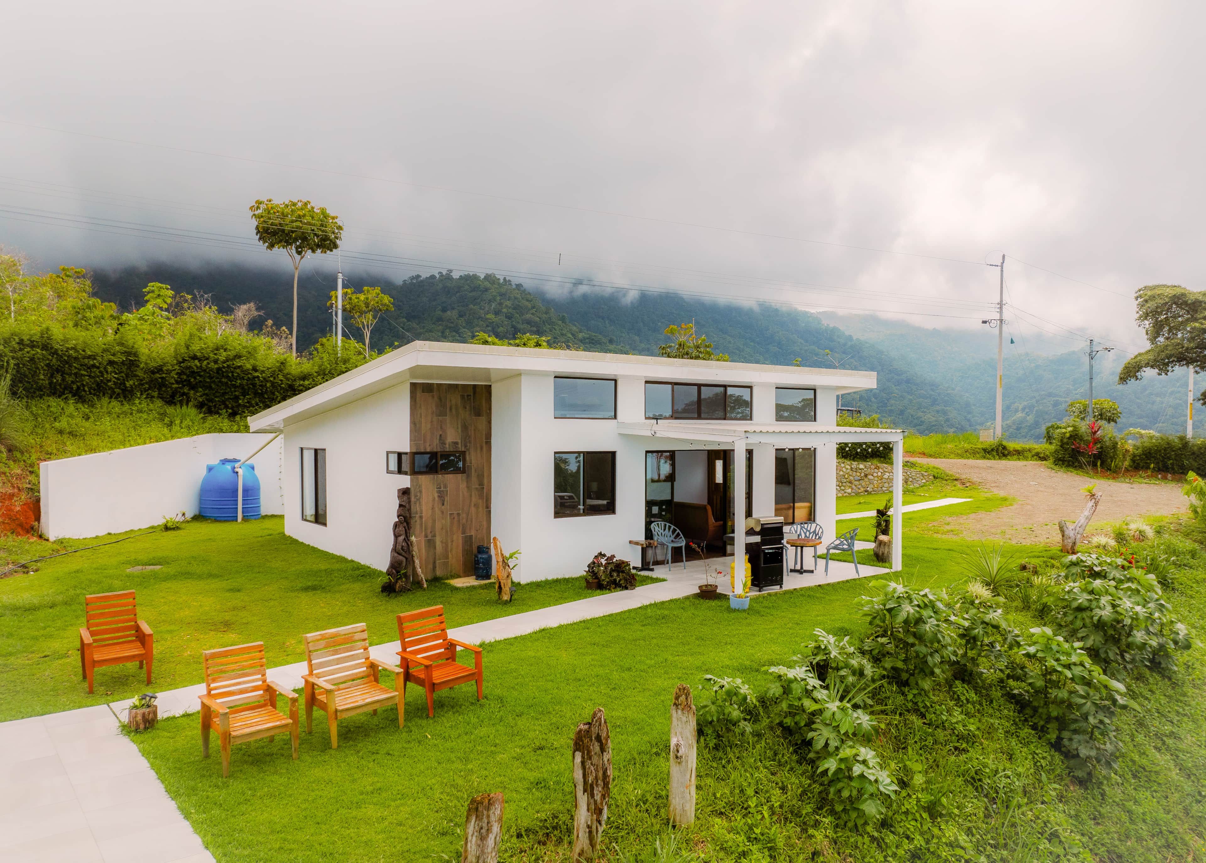 Een modern huis met terras, buitenmeubels en uitzicht op de bergen.