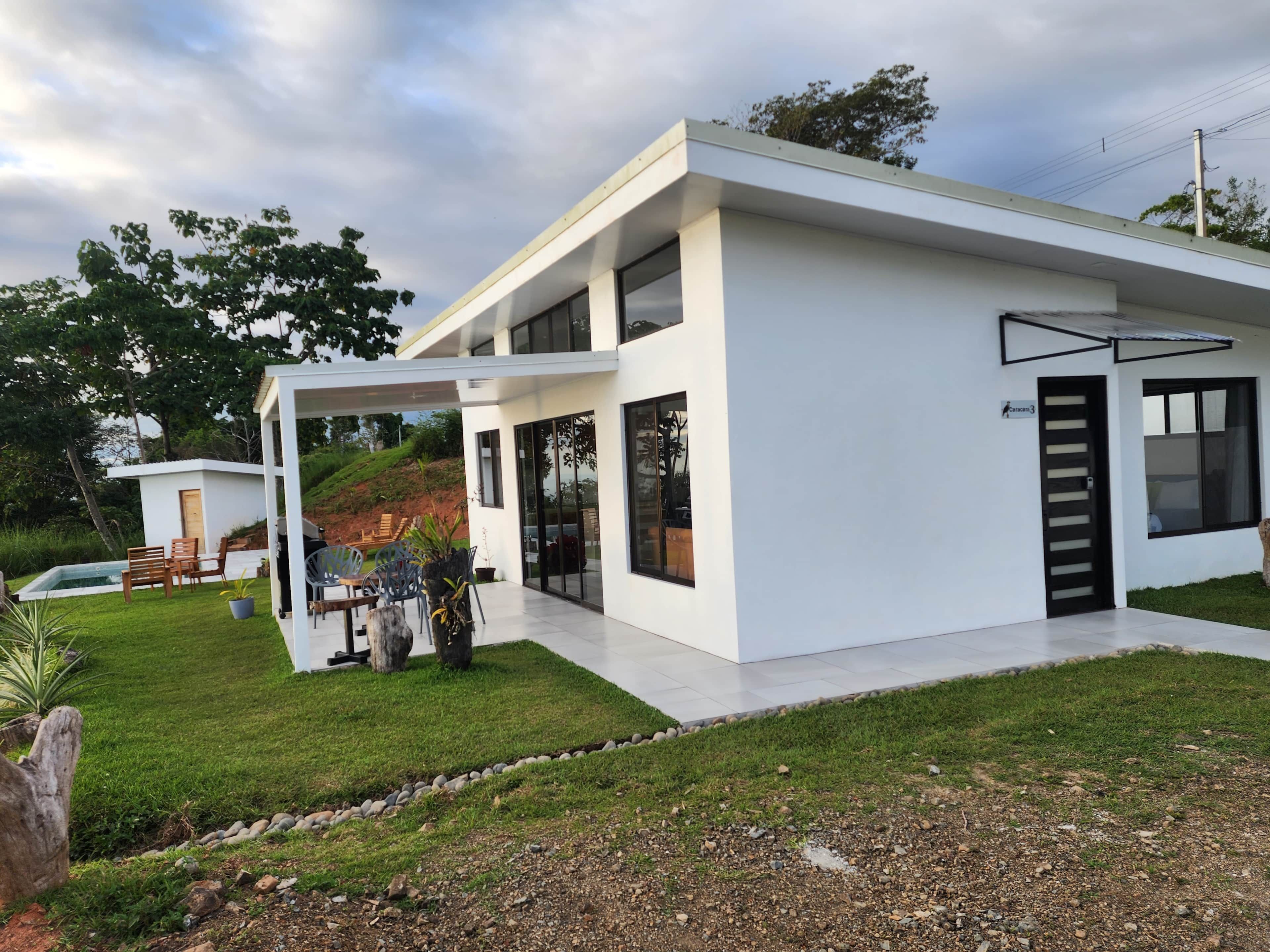 A modern two-story house with a covered patio, a swimming pool, and a well-maintained lawn.