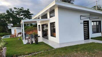 A modern two-story house with a covered patio, a swimming pool, and a well-maintained lawn.