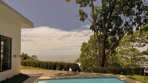A swimming pool with a view of the ocean, surrounded by trees and a modern building. - 3bdr House in Uvita LAPA | 180° Ocean View (Bahía Ballena)