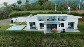 Een modern huis met twee verdiepingen, een zwembad, grote ramen en een terras.