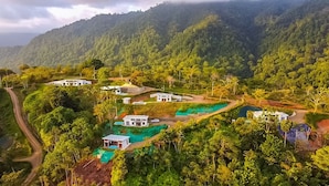 A cluster of modern houses surrounded by lush greenery and hills.