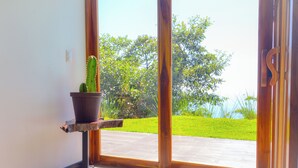 A doorway leading to a patio with a cactus planter and a view of a green lawn and trees.