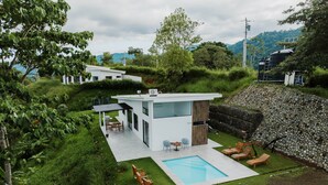 A modern house with a swimming pool, outdoor seating, and a stone retaining wall. - 4bdr House in Uvita QUETZAL | Costa Rica (Uvita)