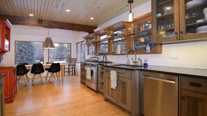 Una cocina moderna con armarios de madera, una isla central y una zona de comedor con sillas.