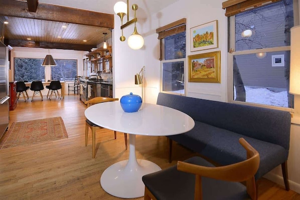 A modern interior with a round white table, blue sofa, and wooden chairs.