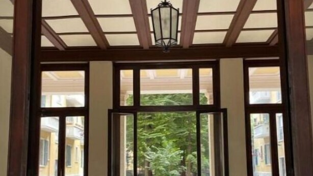 Un pasillo con suelo de baldosas que conduce a un área exterior con vegetación y un edificio al fondo.