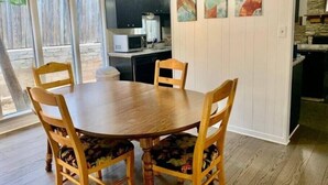 A dining area with a round wooden table and four chairs, a kitchen area with a microwave, and a stone fireplace. - Central & spacious 3bed Near Airport & Downtow

 (Austin)