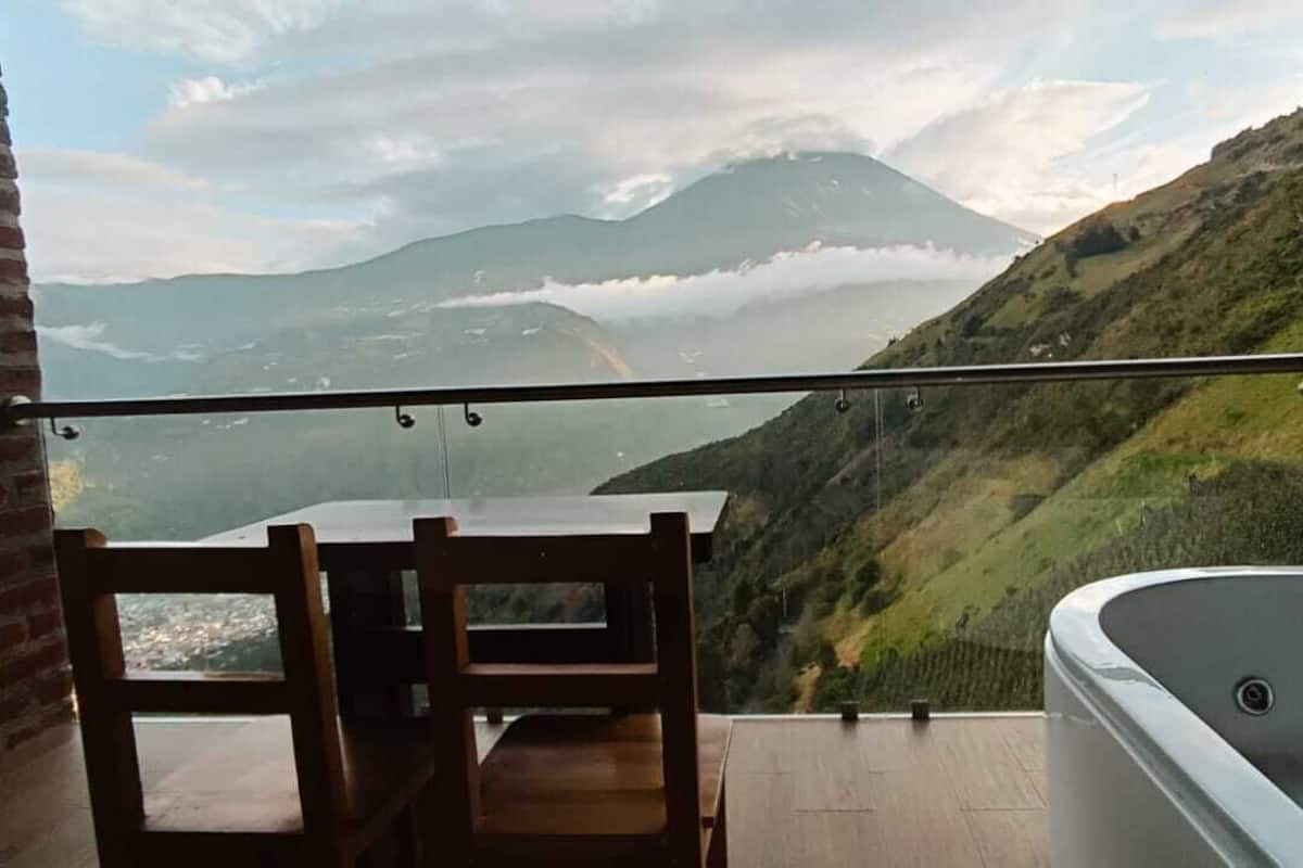 Un balcón con vistas a un paisaje montañoso, una mesa de madera y una bañera.